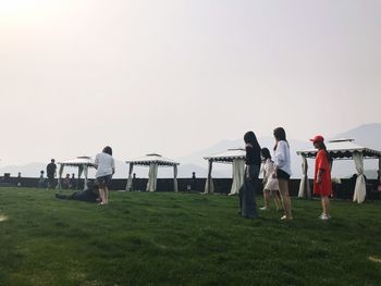 People standing on field against clear sky