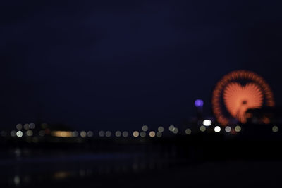 Defocused image of illuminated ferris wheel at night
