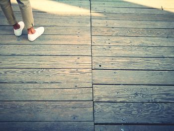 Low section of woman standing on wooden floor