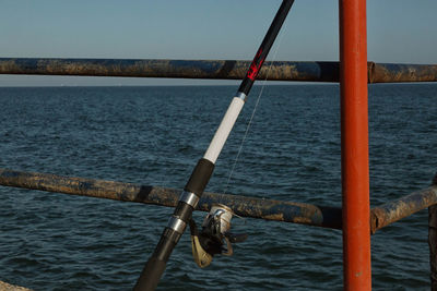 Fishing rod on railing by sea