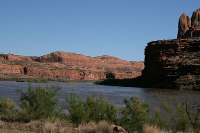 Scenic view of river by mountain against blue sky