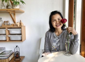 Portrait of smiling young woman holding camera at home