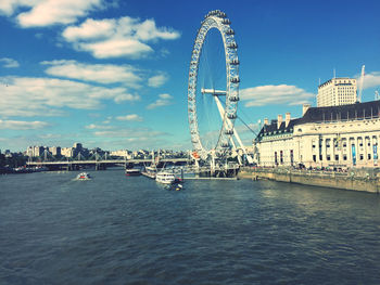 Ferris wheel in city against cloudy sky