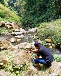 Man standing by rocks in forest