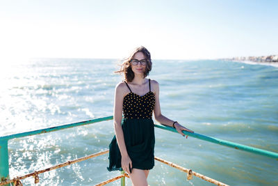 Young woman standing by sea against sky