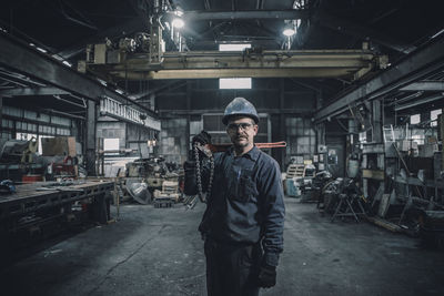 Portrait of male worker carrying work tool while standing in factory