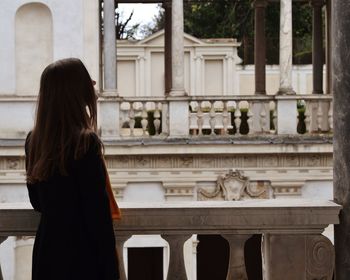 Rear view of woman standing against building