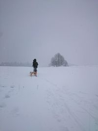 Man skiing on snow covered field against sky