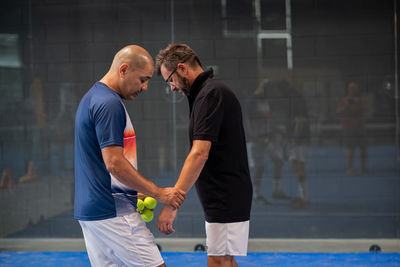 Monitor teaching padel class to man, his student - trainer teaches boy how to play padel 