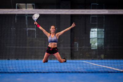 Portrait of beautiful young wimmer girl exulting on indoor padel tennis court