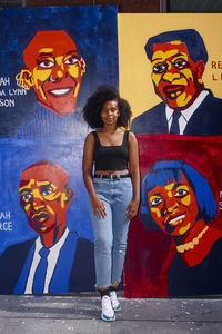 Portrait of smiling young woman standing against graffiti on wall during halloween