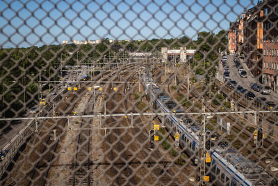 High angle view of railway tracks seen through chainlink fence