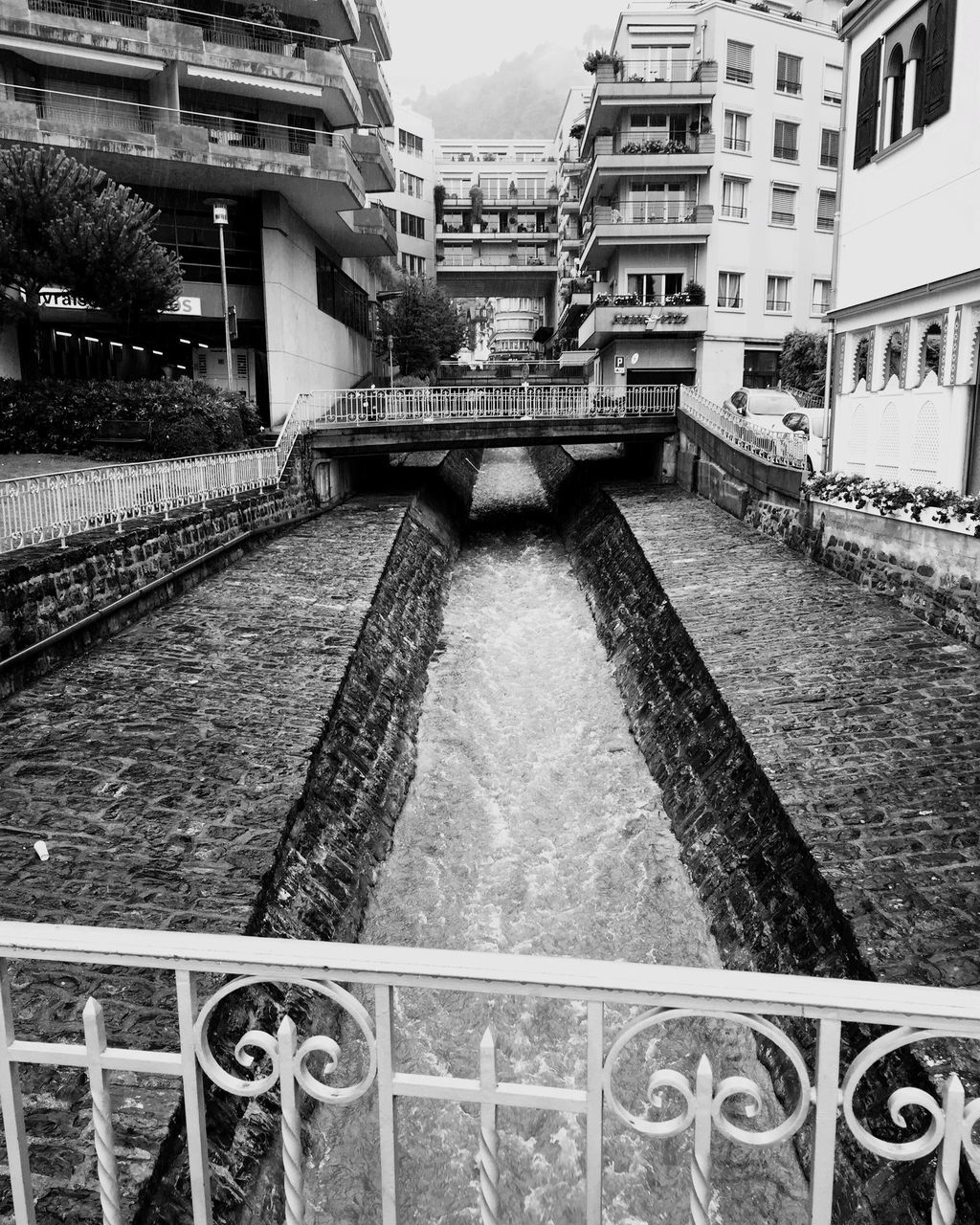 architecture, built structure, railroad track, city, diminishing perspective, the way forward, day, vanishing point, residential building, outdoors, building, sky, no people, canal, city life, residential district, travel destinations