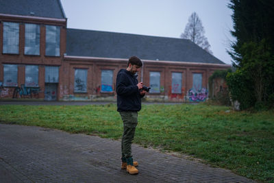 Full length of man photographing on footpath against building