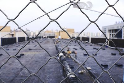 View of city seen through chainlink fence