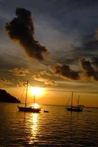 Silhouette sailboats in sea against sky during sunset