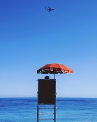 Low angle view of bird flying over sea against clear blue sky