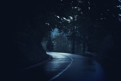 Empty road along trees in forest