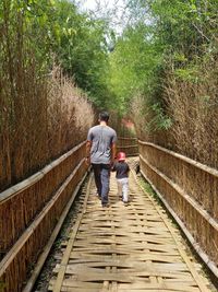 Rear view of father and son walking on footpath