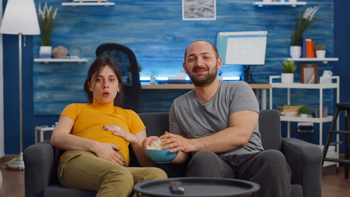 Portrait of couple eating popcorn while watching movie