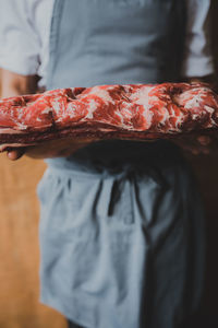 Midsection of person holding meat at home