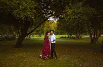 Full length portrait of woman standing by trees against plants