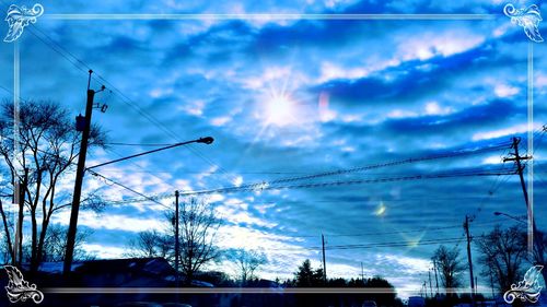 Low angle view of electricity pylon against cloudy sky