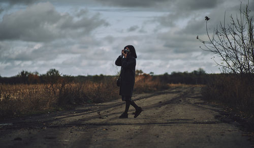 Woman photographing on field against sky