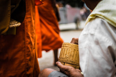 Midsection of man holding wicker basket on street in city