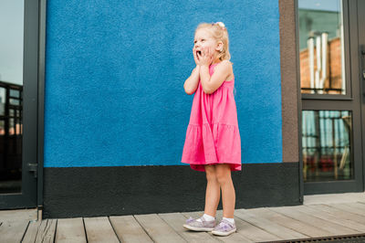 Portrait of young woman standing against wall