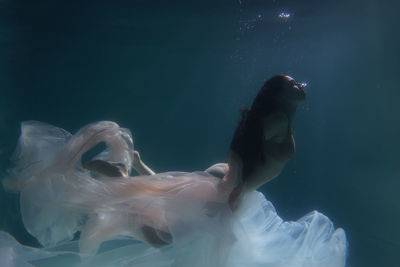 Woman with curtain swimming in pool