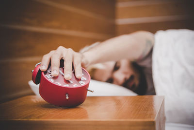 Man pressing alarm clock while sleeping on bed at home