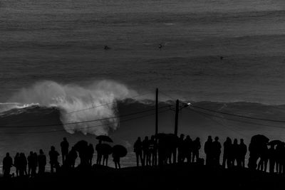 Silhouette people on beach against sky