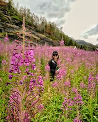 Woman standing amidst flowering plants against mountain