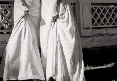 Low section of lesbian couple during wedding ceremony standing against on field