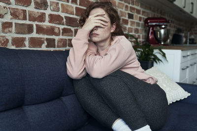 Young woman sitting on sofa at home