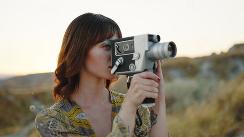 Young girl shoots with the 8mm vintage camera in the nature among the bubbles