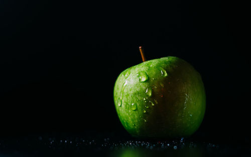 Close-up of wet apple against black background