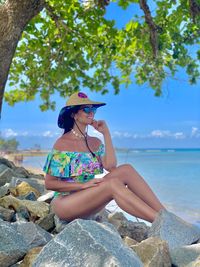 Woman sitting on rock by sea