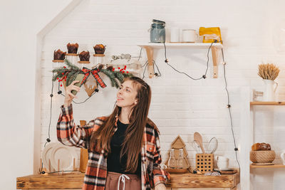 Full length of woman with arms raised standing against wall