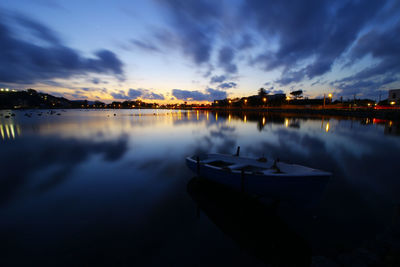 Boats moored in lake against sky at sunset