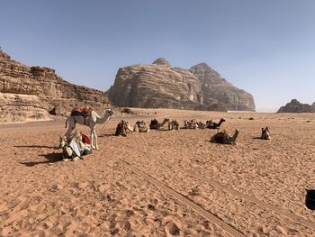 People on rock formations in desert against sky