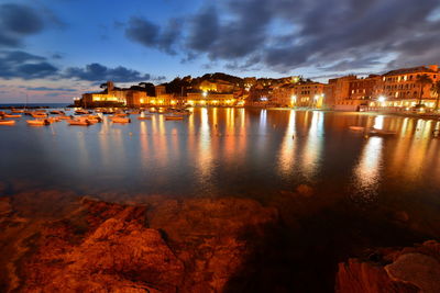 Illuminated sestri levante by sea against sky at dusk