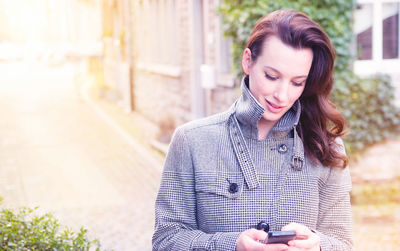 Close-up of woman using mobile phone while standing on footpath