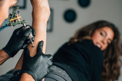 Close-up of mam making tattoo on woman leg