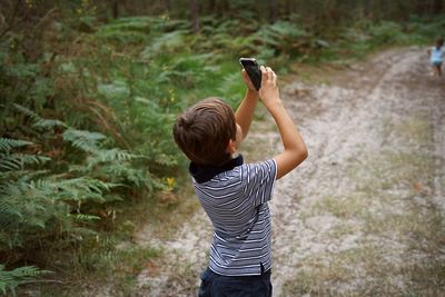 Rear view of child photographing with mobile phone