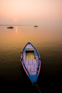 Boat in sea against sky during sunset