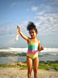 Full length of girl standing at beach against sky