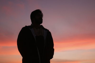 Silhouette man standing against orange sky