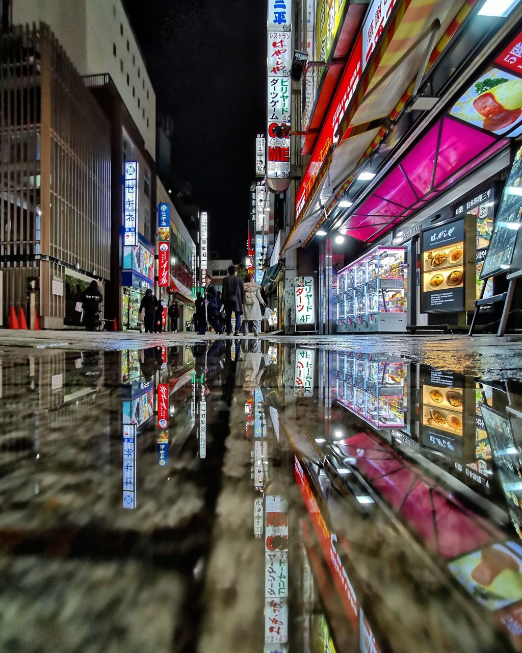 REFLECTION OF ILLUMINATED BUILDING IN PUDDLE